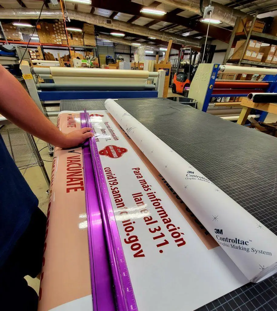 A person in a print shop is working on large banners