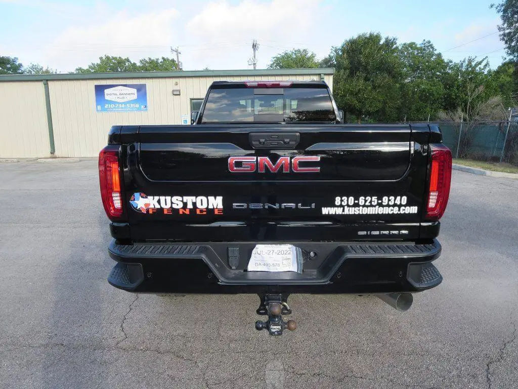 Black GMC truck with a custom fence ad, contact info, and website info on the tailgate.
